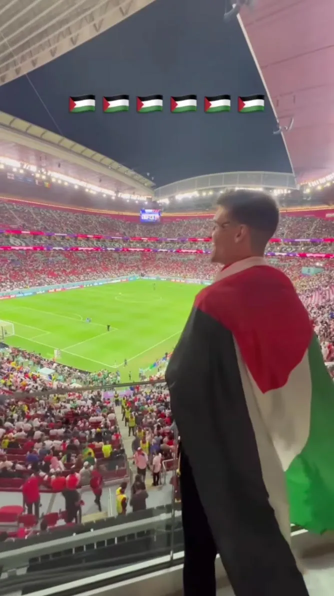 A young man dressing a Palestine flag in a World Cup stadium